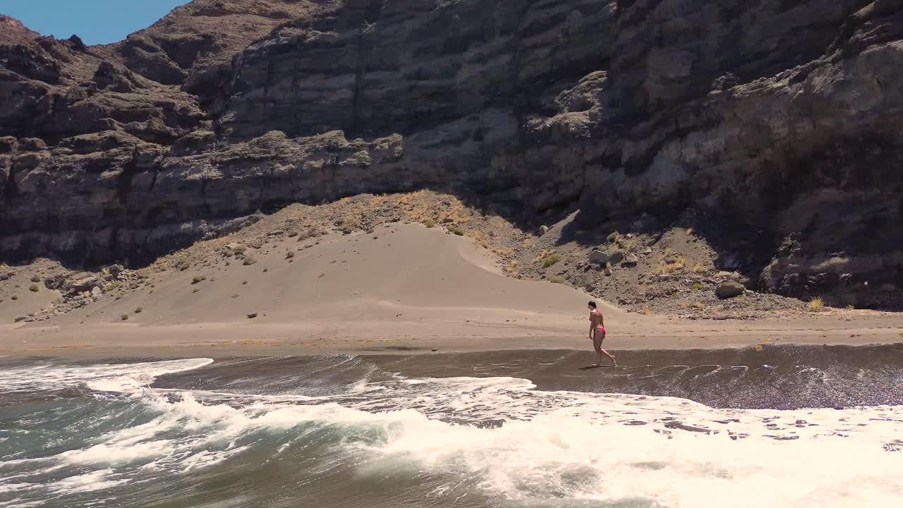 escena idílica de una mujer relajándose relajándose en una playa virgen virgen en gran canaria, españa durante el verano en vacaciones