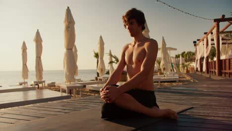 The-guy-took-a-special-position-for-yoga-and-meditation.-Zen-style-in-the-morning-on-the-beach