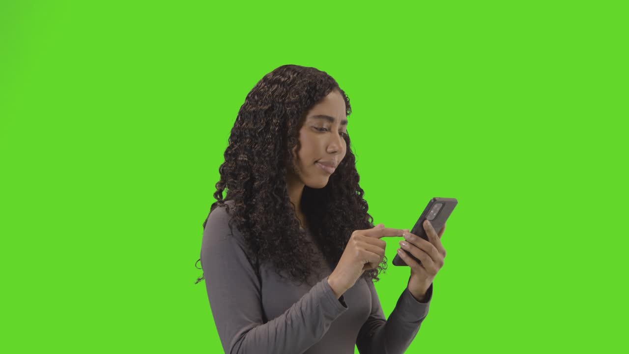 Woman Looking At Mobile Phone And Celebrating Good News Against Green Screen 2