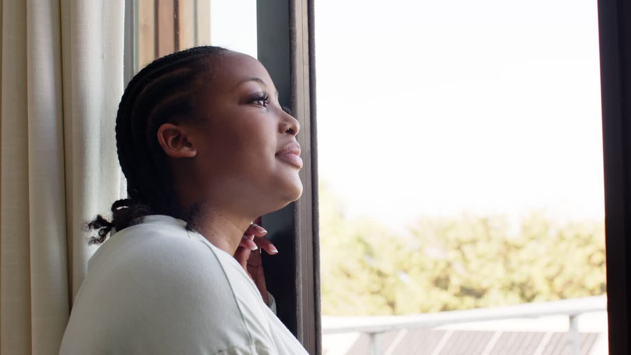 Una luce solare soffusa filtra dalla finestra, una donna afroamericana alza il mento e sorride, spazio per il testo