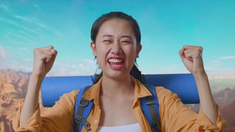 close up of asian female hiker with mountaineering backpack screaming goal celebrating the success while traveling at the top of mountain