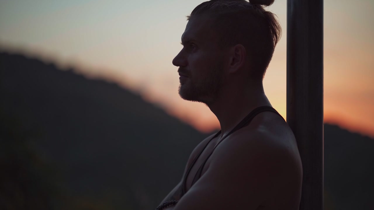 Man Standing in Silhouette Against Sunset Over Mountains