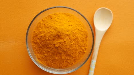 turmeric powder in a bowl with wooden spoon