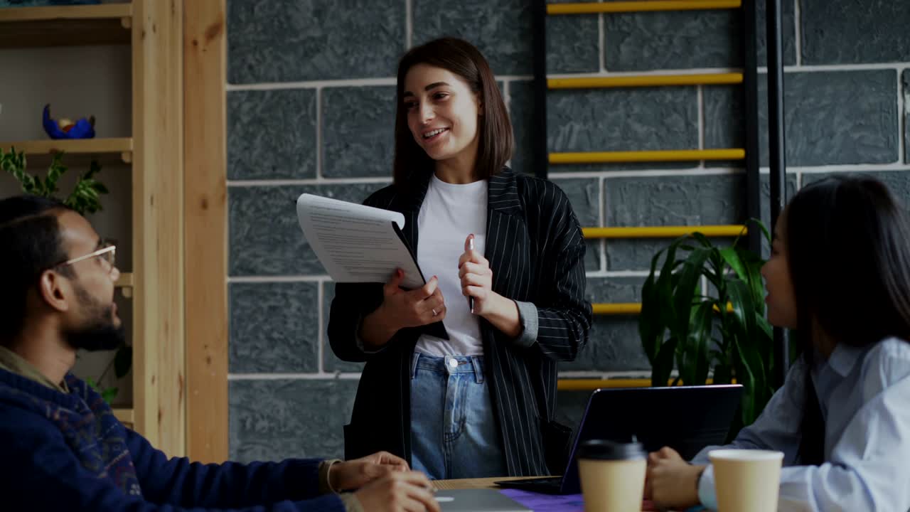 líder femenina yong hablando y discutiendo nuevas ideas con el equipo creativo durante la lluvia de ideas de proyectos de puesta en marcha en oficinas modernas interiores