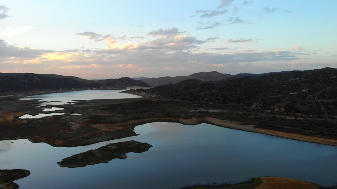 넓은 공중 드론 4k는 아름다운 일몰에 캘리포니아 남부 오렌지 카운티에 있는 건조하고 가뭄에 시달리는 어바인 호수 저수지 위로 날아갑니다.