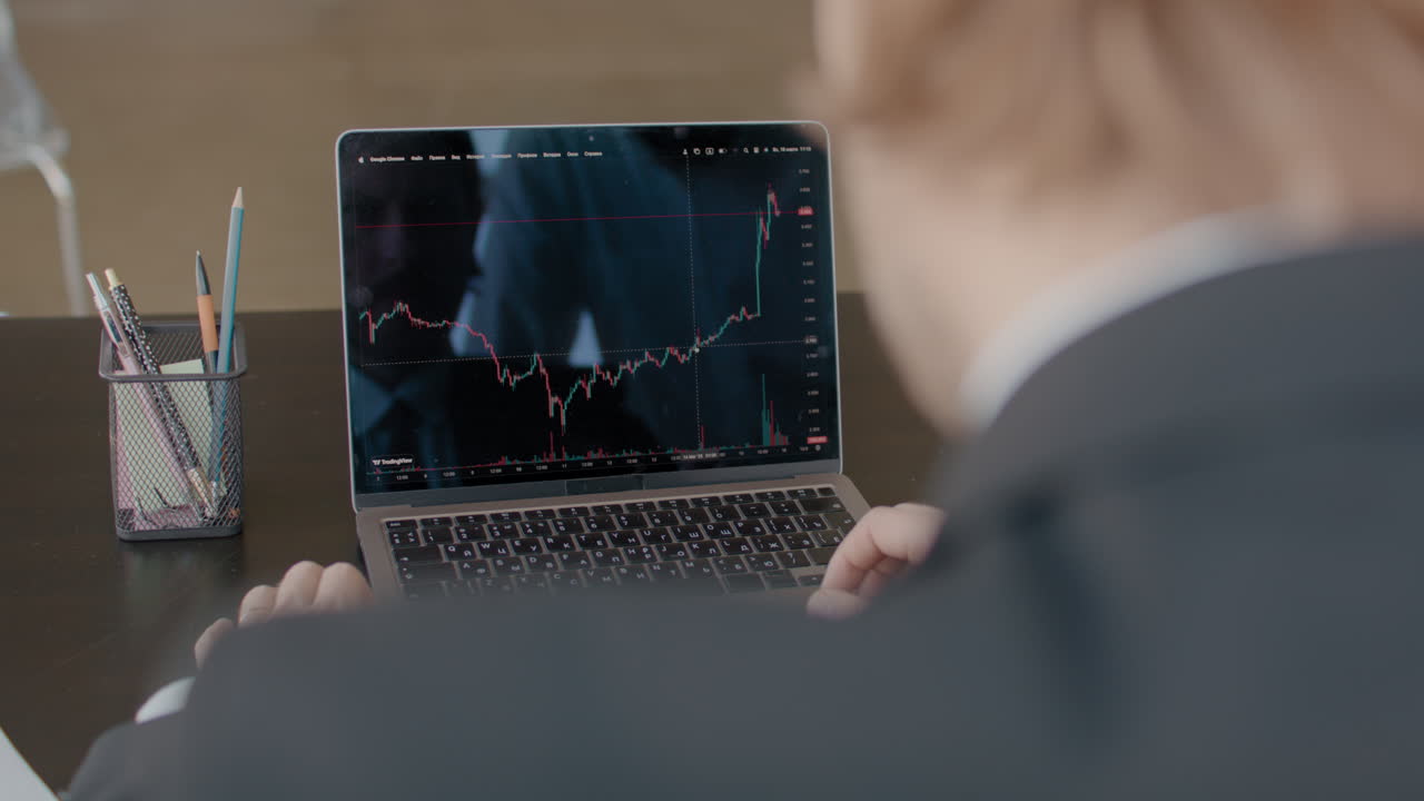Person analyzing stock market data on a laptop