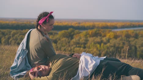 una joven pareja de lesbianas descansa después de una caminata en la hierba de otoño