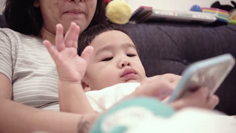 asian baby using smartphones with mom on the bed