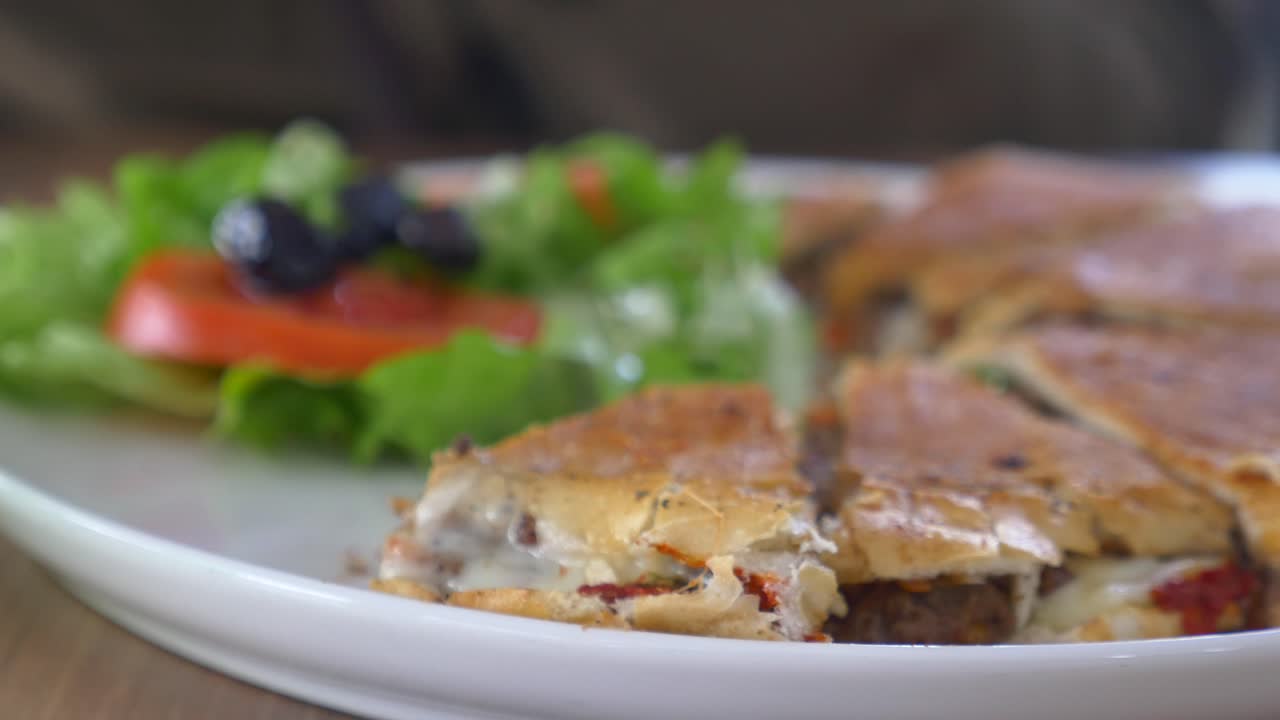 Person eating a delicious, sliced, baked sandwich with salad