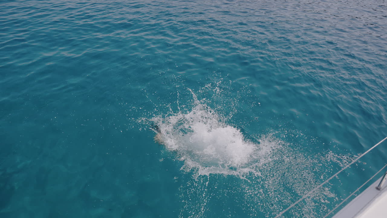 Person Jumping into Turquoise Water from Boat