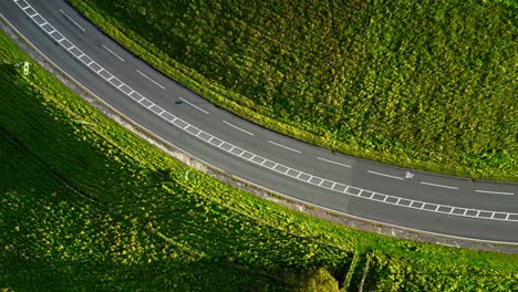 drone shot of cars passing on rural hill corner