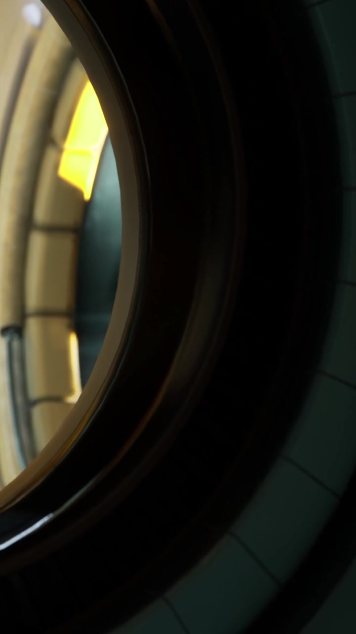 View through a round window showing a light source and wall details