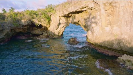 Natural-stone-arch-in-tropical-ocean,-aerial-forward-dolly-in-summer-day