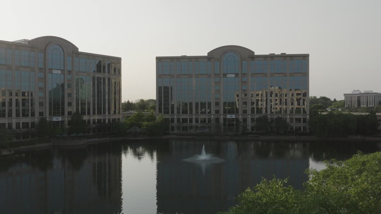 Forward moving drone shot capturing buildings of Centennial Lakes Park during afternoon in Edina, USA.