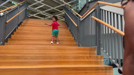 intrépido e independiente negro niño negro de 3 años subiendo escaleras seguido por su madre
