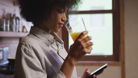 mixed race woman drinking orange juice at home