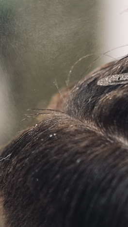 spraying water on hair of man client with hairpin at hairdo procedure in salon extreme closeup slow motion. professional beauty and barbershop service