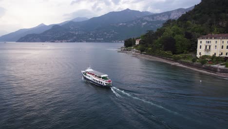 Transbordador-Que-Viaja-En-La-Superficie-Del-Agua-Del-Lago-Como-Con-Hermosos-Alpes-De-Fondo,-Aéreo