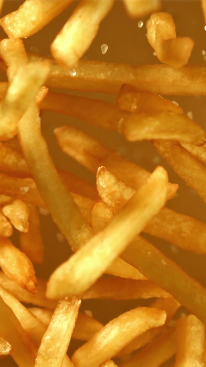 Sal cayendo sobre patatas fritas doradas y crujientes