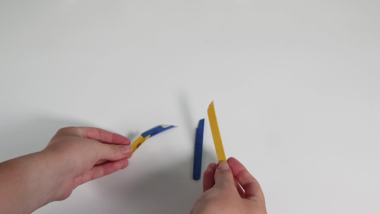 Hands bending and breaking colored wax sticks