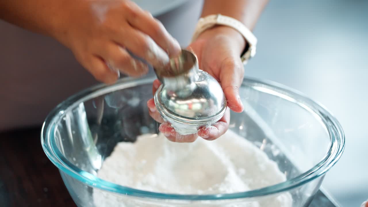 A woman's hands carefully pack a powder mixture into a round metal mold to create a natural, homemade bath ball, a close-up showing the process of crafting artisanal spa and beauty products
