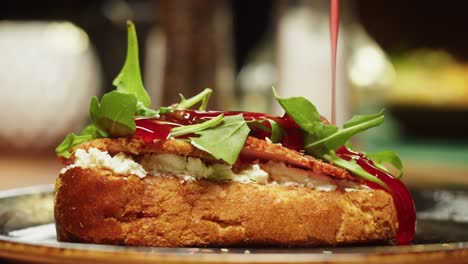 cooking prosciutto sandwich close-up. pouring tomato sauce on toast bread with ham, spinach and cottage cheese. tasty snack. bruschetta with meat and lettuce