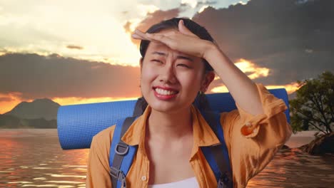close up de una excursionista asiática con mochila de montaña mano frente sonriendo y mirando la distancia mientras está de pie en un lago durante la hora del atardecer