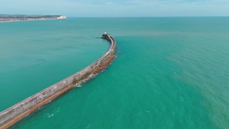 a curved seawall extending into turquoise ocean waters, aerial view