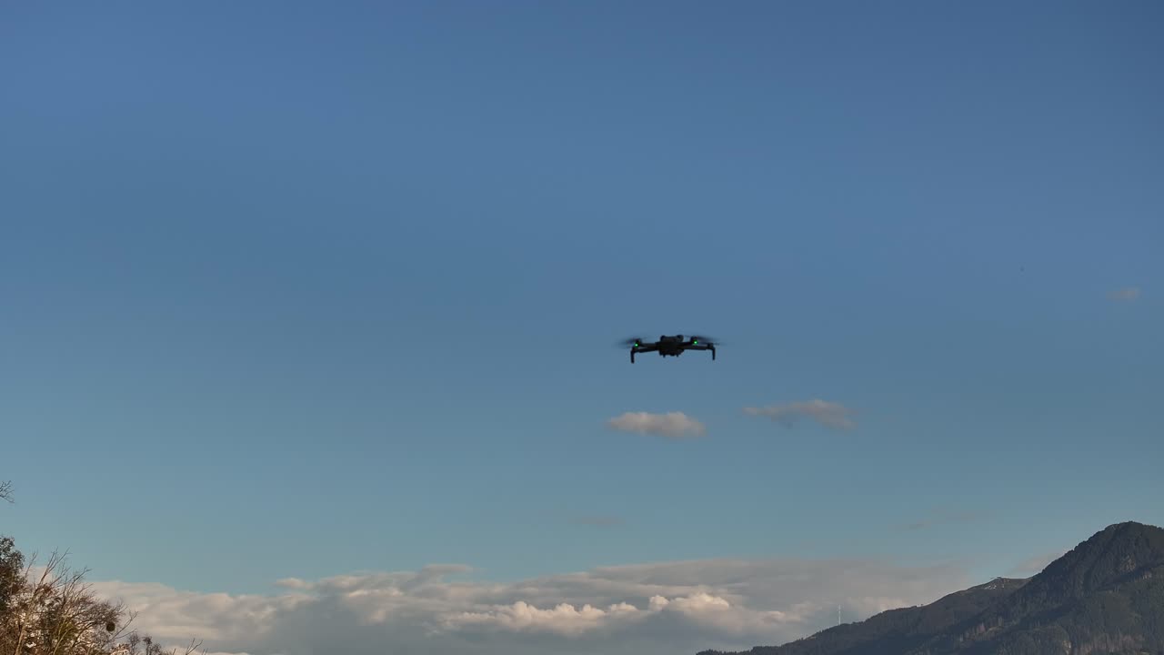 drone flies against a clear blue sky, with mountain peaks faintly visible in the background