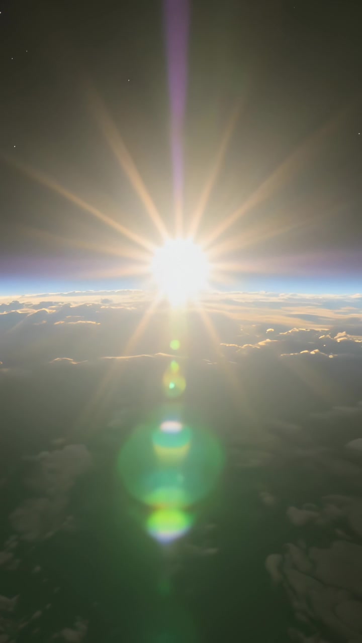 Vertical video: Emerging sun lifting above horizon over clouds, lighting cloud tops and lens flares