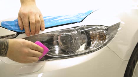 hombre cubriendo el coche con cinta de poliuretano de vinilo. películas para el coche. pegatina película protectora en el faro del coche