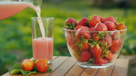 pour the juice into a glass next to a plate of fresh strawberries 1