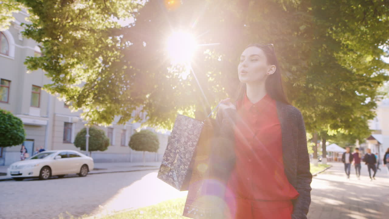 쇼핑백을 들고 거리를 걷고 있는 빨간 드레스를 입은 세련된 여성