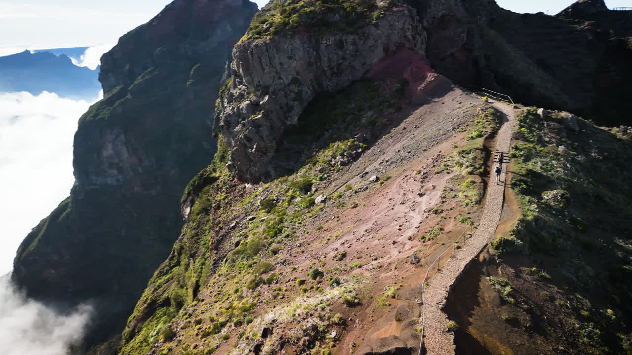 couple of people walking hike trail mountain ridge high above the clouds in Madeira, aerial view