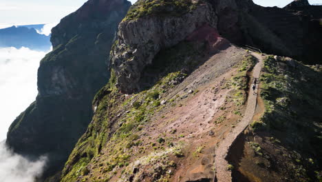 couple of people walking hike trail mountain ridge high above the clouds in madeira, aerial view
