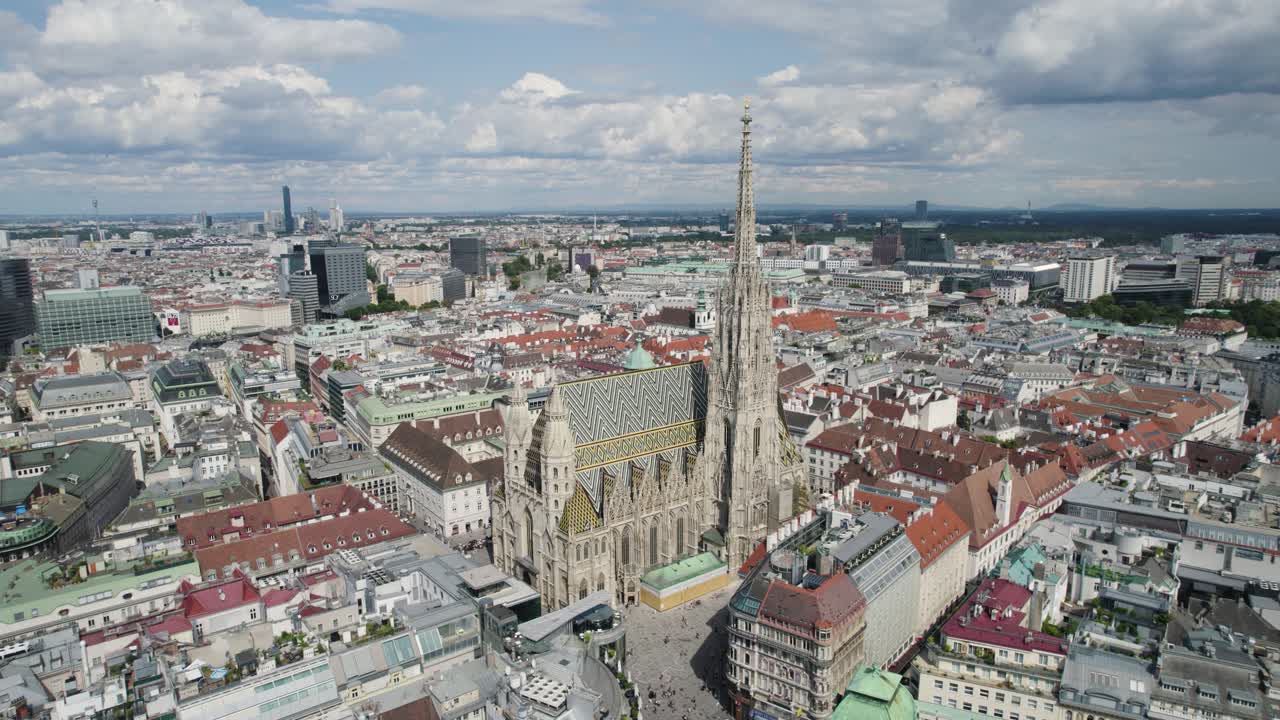 Aerial view of St. Stephen's Cathedral in Vienna with surrounding cityscape, orbit around ornate tiled roof
