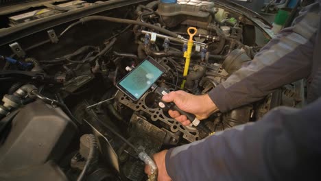 manos de mecánico de automóviles comprobar el motor del vehículo con endoscopio técnico con cámara rotativa y teléfono móvil. reparación de la cabeza del motor y las válvulas.