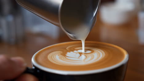 barista pouring milk for latte art in a coffee cup