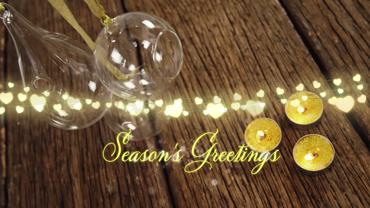 Animation of text, season's greetings, in yellow, string lights, candles and christmas decorations