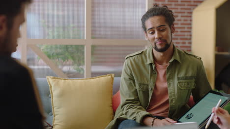 young-mixed-race-businessman-using-tablet-computer-showing-clients-business-ideas-pointing-at-screen-entrepreneurs-brainstorming-enjoying-teamwork-connection-in-modern-office