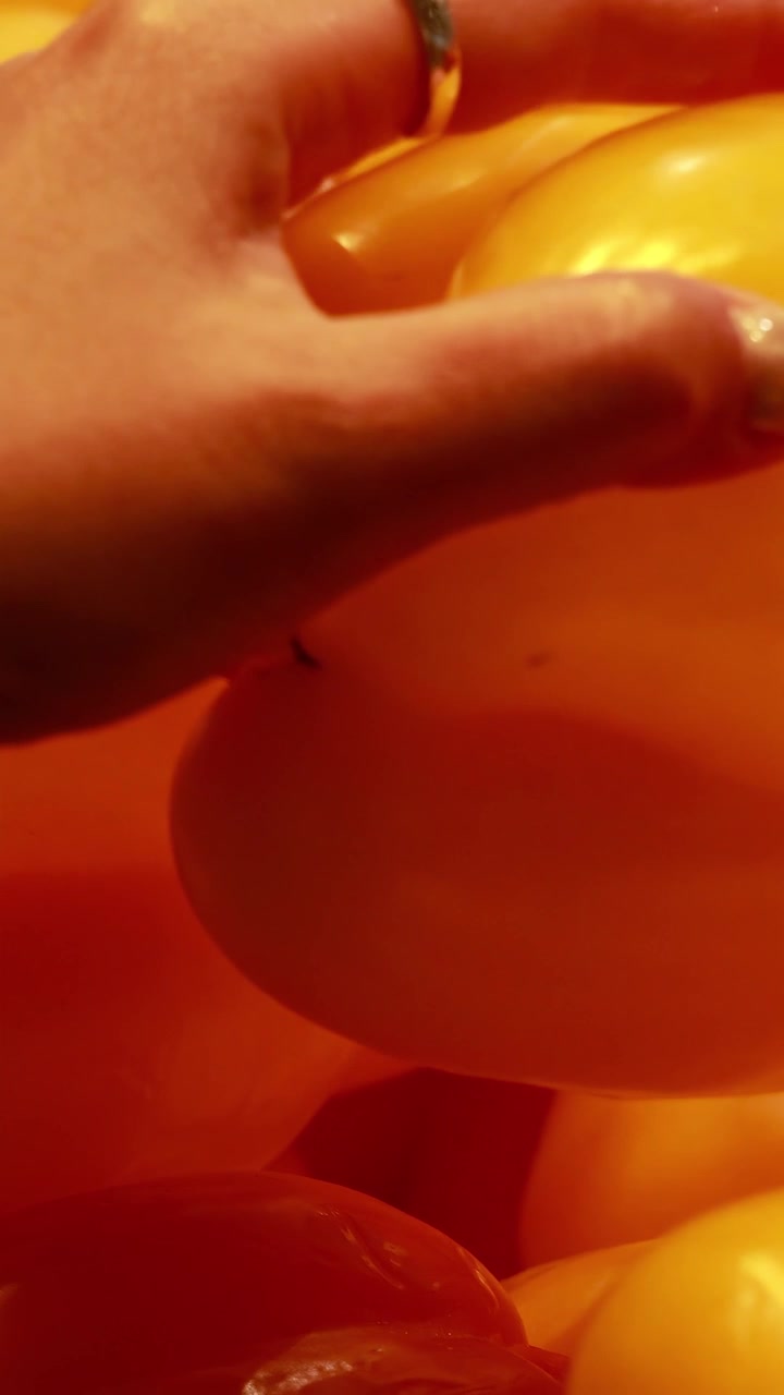 Una mano esamina peperoni gialli vivaci sotto un'illuminazione calda in un ambiente da supermercato.