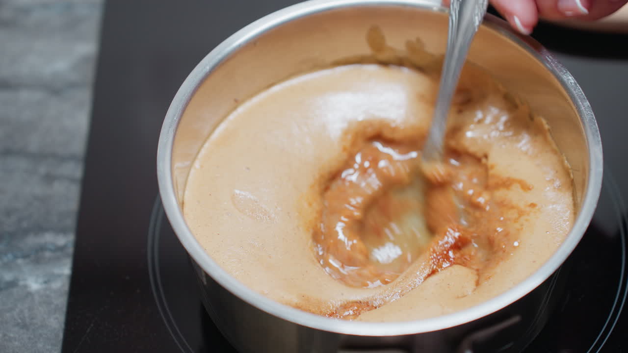 Close-up of chef stirring a pot of thick soup on an electric stove, the rich, creamy texture blends as the spoon moves, creating a smooth consistency