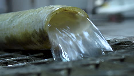 plastic pipe expelling water into drain on factory floor