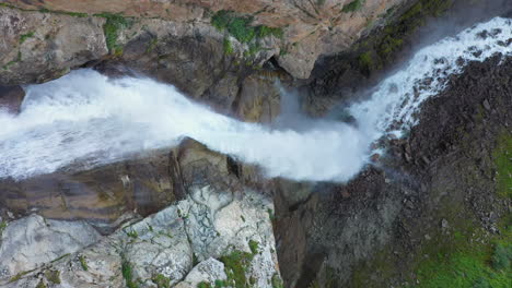 Downward-angle-descending-drone-shot-Barskoon-Waterfall-in-Fairy-Tale-Canyon-in-Kyrgyzstan,-cinematic-aerial-footage