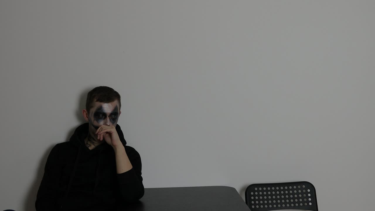 테이블 에 어두운 조롱거리 메이크업으로 앉아있는 혼자 남자