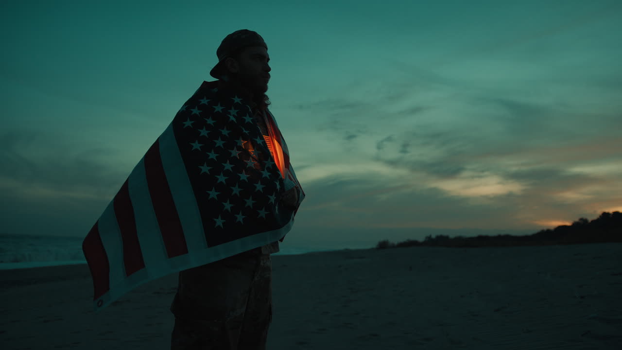 At sunset the silhouette of a patriotic American Memorial soldier wears the flag
