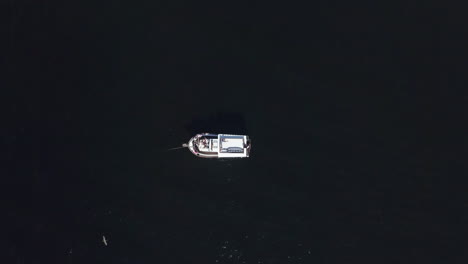 Top-Down-Aerial-Shot-of-Lone-Boat-in-Dark-Waters-of-Guanabara-Bay-in-Rio-De-Janeiro,-Brazil