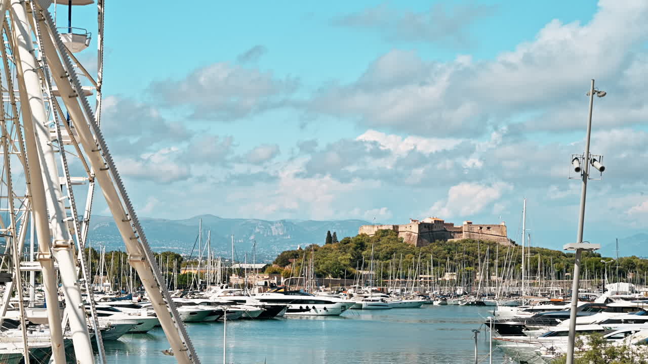 View of the sea port in Antibes, France. Moored boats and yachts, Fort Carre on the background, greenery