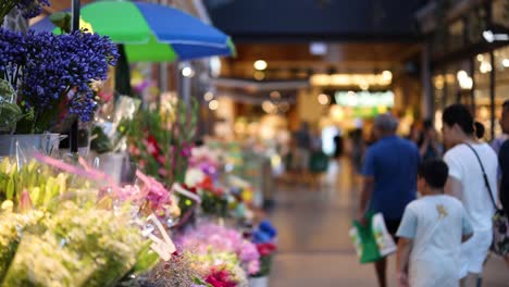 people walking past vibrant flower stalls