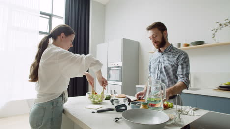 Junges-Paar-Spricht-Und-Bereitet-Gemeinsam-Essen-In-Einer-Modernen-Küche-Zu